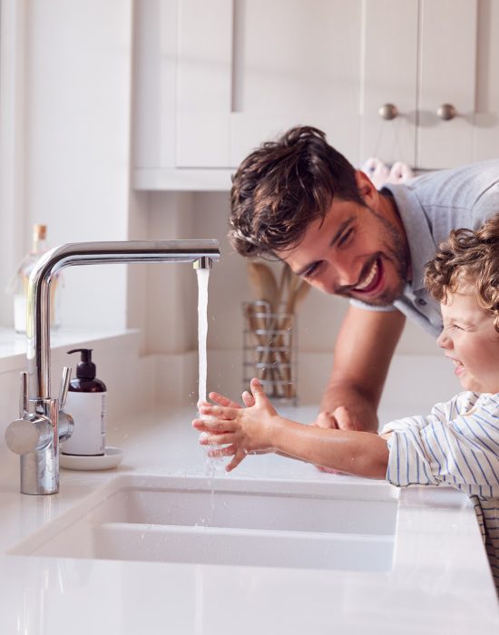 Father Helping Son To Wash Hands With Soap At Home To Stop Spread Of Infection In Health Pandemic